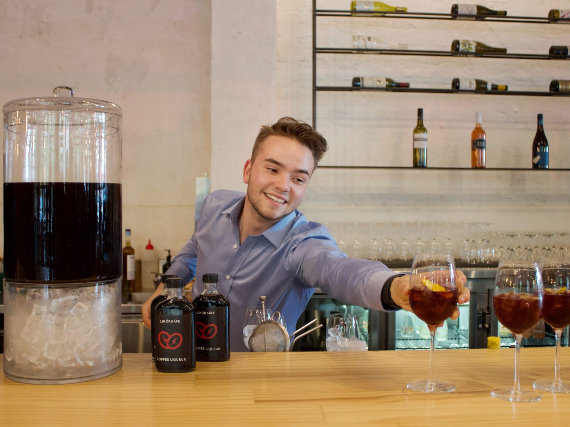 A bartender preparing cocktails with coffee liqueur and lemon at the bar counter.