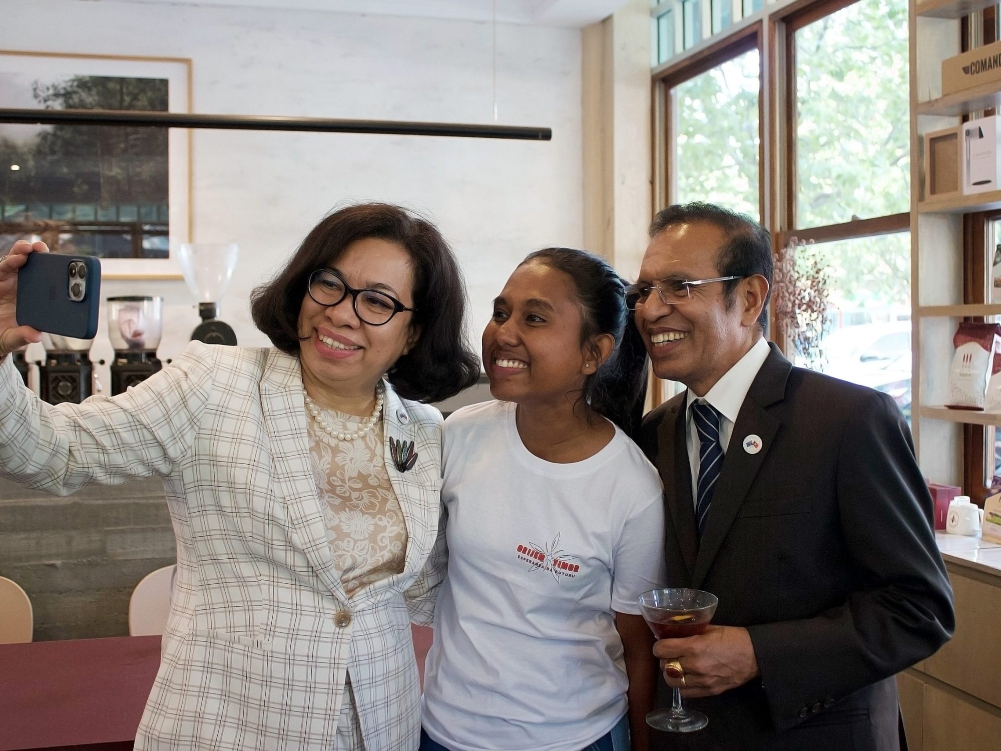 Three individuals taking a selfie in a stylish cafe environment.